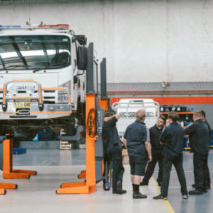 Daniels Automotive employees around a lifted vehicle discussing auto electrical repairs