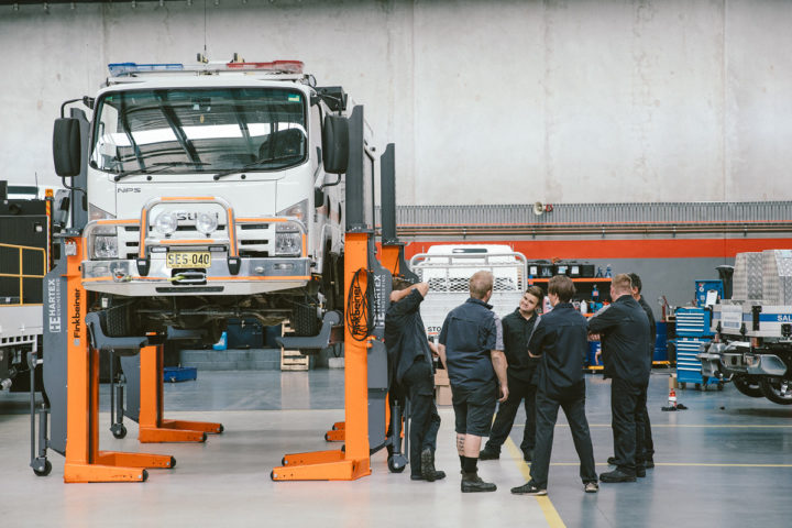 Daniels Automotive employees around a lifted vehicle discussing auto electrical repairs